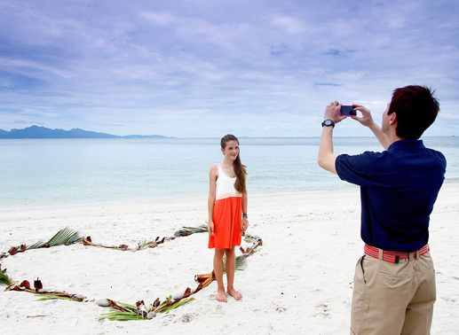 Johan (Lawrence Wong) fotografiert Sina (Leonie Brill) am Traumstrand von Malaysia. Bild: Sender